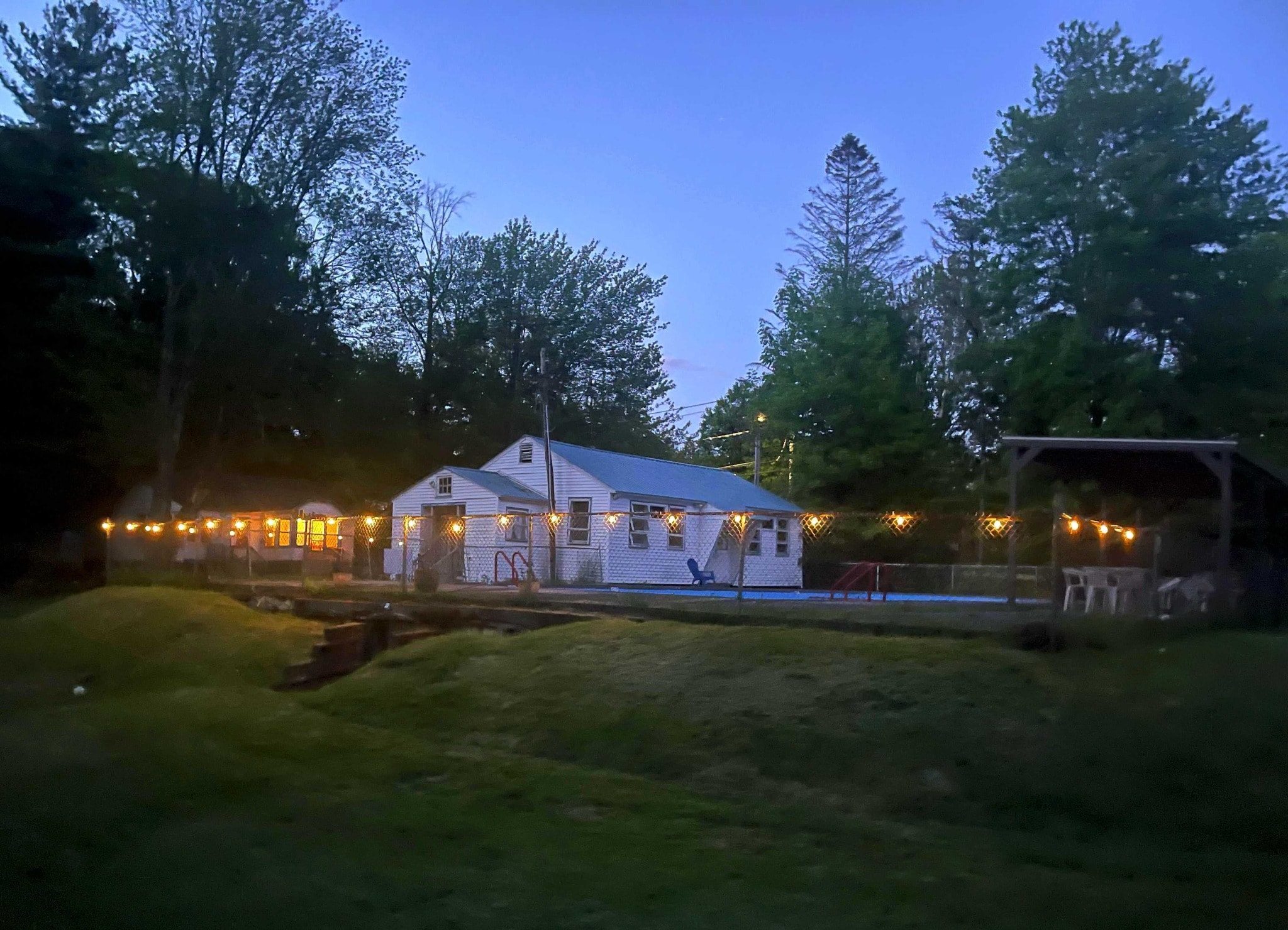 Carefree Acres clubhouse and pool at dusk with string lights